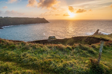 Beautiful dramatic Summer sunrise over Lizard Point in Cornwall UK with lovely glowing sky and cloudsの写真素材