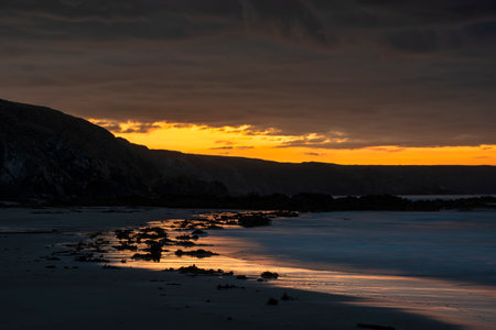 Absolutely stunning sunrise landscape image of Kennack Sands in Cornwall UK wuth dramatic moody clouds and vibrant sunburstの写真素材