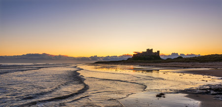 Beautiful landscape image of Northumberland beach in Northern England during Winter sunriseの写真素材