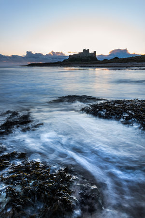 Beautiful landscape image of Northumberland beach in Northern England during Winter sunriseの写真素材