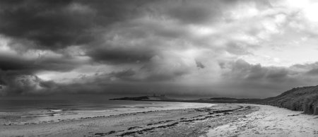 Beautiful unusual  black and white moody Winter landscape of snow on Embleton Bay beach in Northumberland Englandの写真素材