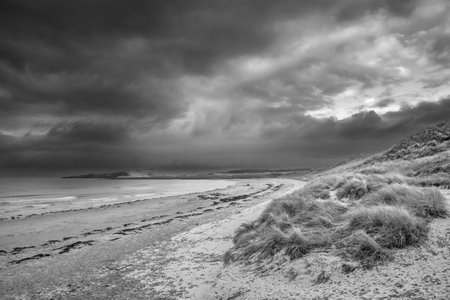Beautiful unusual moody Winter  black and white landscape of snow on Embleton Bay beach in Northumberland Englandの写真素材