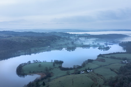 Stunning drone aerial landscape image of cloud inversion around Esthwaite Water in Lake District during Spring sunrise blue hourの写真素材