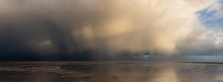 Stunning dramatic stormy skies over ocean panoramic landscape with distant heavy rainfallの写真素材