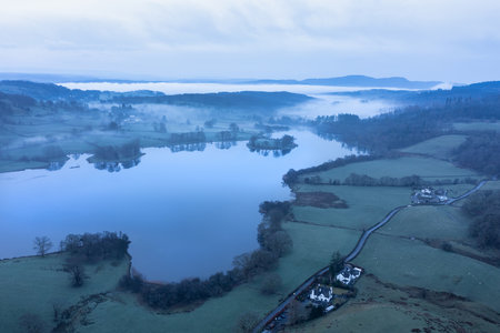 Stunning drone aerial landscape image of cloud inversion around Esthwaite Water in Lake District during Spring sunrise blue hourの写真素材