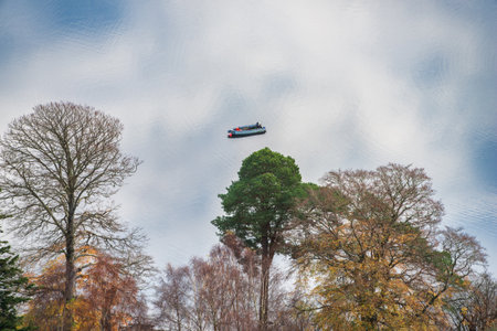 Lovely abstract landscape image of boat floating in sky reflection in lake and forest imageの写真素材