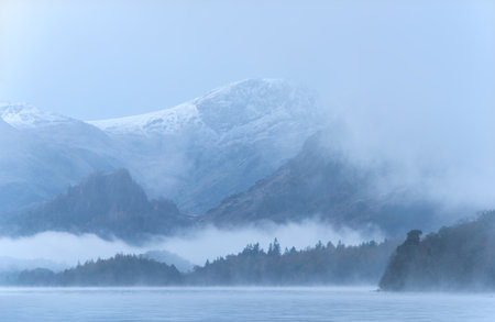 Absolutely stunning atmospheric landscape image of Derwentwater during foggy sunrise in Autumnの写真素材