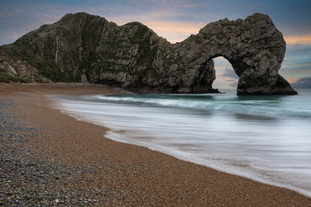 Stunning landscape image of rock arch and cliffs on Jurassic Coast in England during Winter sunsetの写真素材
