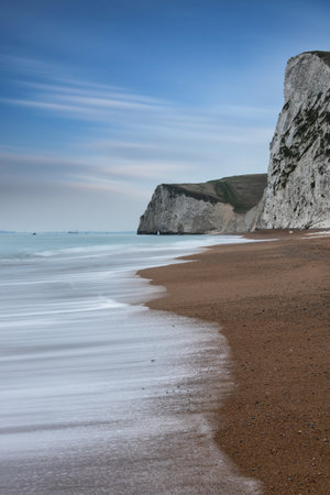 Stunning landscape image of rock arch and cliffs on Jurassic Coast in England during Winter sunsetの写真素材