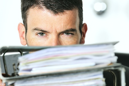 busy man hiding behind a stack of filesの写真素材