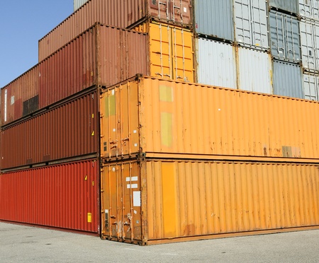 Cargo shipping containers stacked at harbor freight terminal under clear blue sky