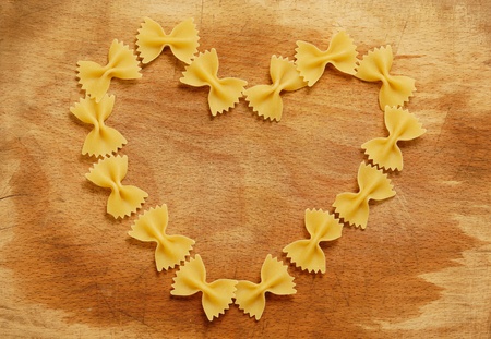 Italian farfalle pasta forming a heart on wood backgroundの写真素材