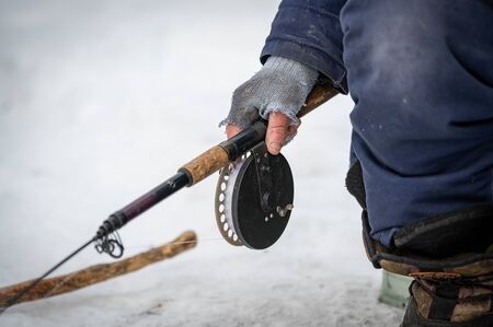 Baikal lake, Siberia, Russia - March 05, 2020 : Winter ice fishing. A fisherman is fishing on...