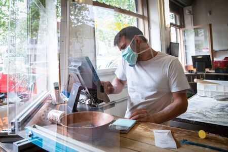 Man is working in a pizza restaurant drive with his mask and covid 19 protection. Pandemic situation