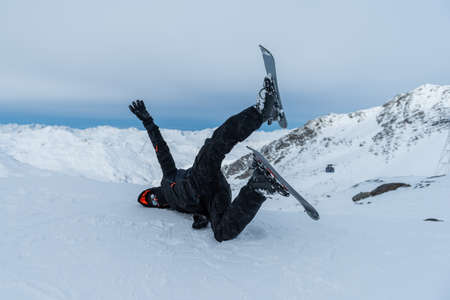 a man skier falling in the snow on top of the mountain