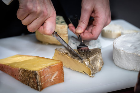 a waiter is cutting a cheese for his client in a hotelの写真素材