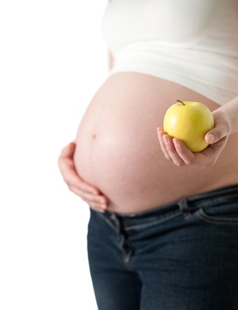 Pregnant woman holding an apple, isolated on white background の写真素材