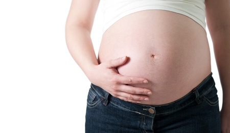 pregnant woman holding her belly with one hand on white background