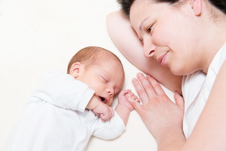 mother watching her month old son sleeping in bedの写真素材