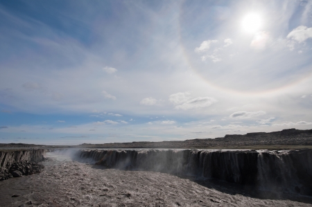 Sun with circular rainbow effect in the sky above Selfoss waterfall, Iceland