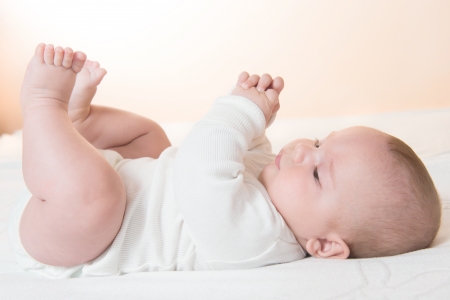 cute little baby lying on his back resting on the blanket, orange backgroundの写真素材