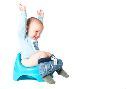 Happy one year old boy having fun on the chamber pot, isolated over white backgroundの写真素材