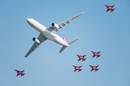 PAYERNE, SWITZERLAND - SEPTEMBER 6: Flight of Airbus A-330 of Swiss Airlines followed by Patrouille Suisse aerobatic team in close formation on AIR14 airshow in Payerne, Switzerland on September 6, 2014のeditorial素材