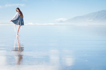 Young pretty stylish woman running at amazing New Zealand beach with blue ocean, enjoy her vacation and summer sunny dayの写真素材