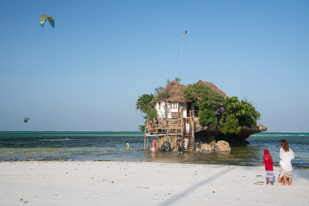 MICHANWI PINGWE BEACH, ZANZIBAR - DEC 24, 2017: Kitesurfer jumping high into the air near the Rock restaurant located south east of the island, on the Michamwi Pingwe peninsula, Zanzibarのeditorial素材