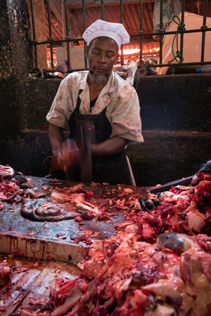 STONE TOWN, ZANZIBAR - DEC 31, 2017: Seller prepare fresh beef meat at Darajani Market in Stone Town, Zanzibarのeditorial素材
