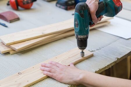 Detail of drill making hole into wooden plank