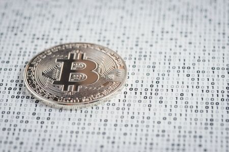 Cryptocurrency coin - silver Bitcoin on black and white binary 1 and 0 background