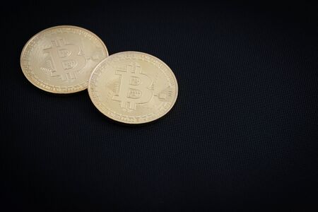 Two golden bitcoins on black background