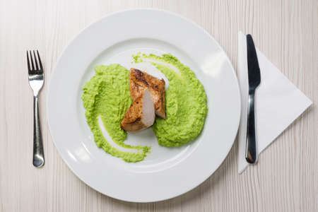 Detail of grilled chicken steak with mashed green peas up on a plateの写真素材