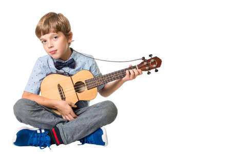 young adorable boy playing the ukulele, isolated on white background with space for text