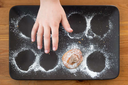 Child's hand reaching for last cookie on trayの写真素材