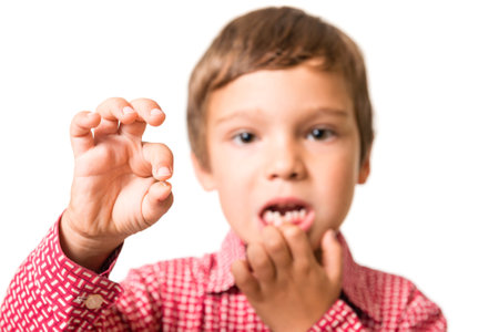 young boy showing his first lost milk-tooth in his hand, isolated on white background