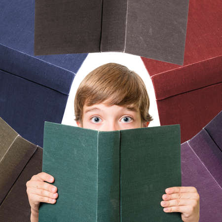 young adorable boy looking surprised from behind big book, isolated on white background