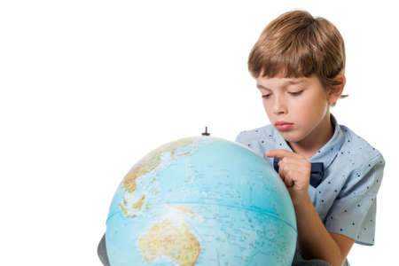 young adorable boy looking at globe, isolated on white background with space for textの写真素材