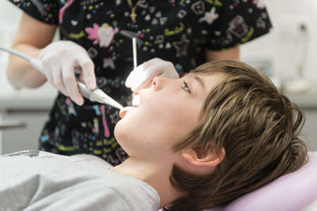 Dentist examining young boy's teeth in clinicの写真素材