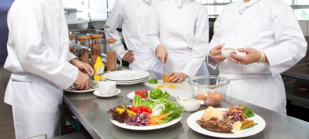 A senior chef giving cooking lesson to young chefsの写真素材