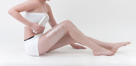 A woman wrapping her leg with plastic wrapperの写真素材