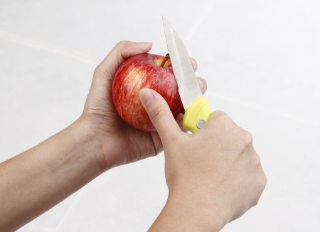 A woman pealing apple with knifeの写真素材