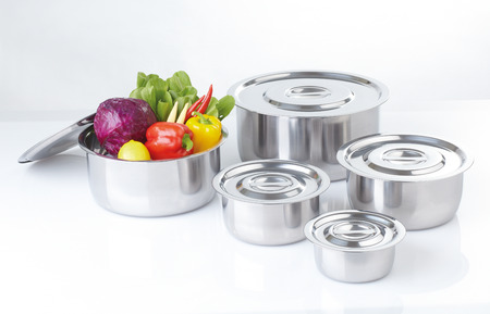 Set of stainless pots with lids and vegetableの写真素材