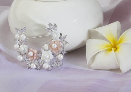 Beautiful diamond and pearl brooch in flowers shape on white clothの写真素材