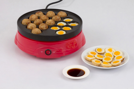 Takoyaki ball cooking machine display with takoyaki and fried eggsの写真素材