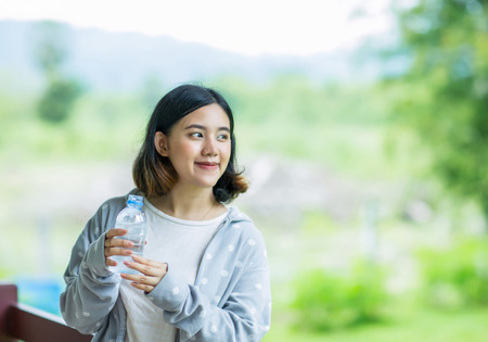 Pretty young asain girl holding a bottle of cold water