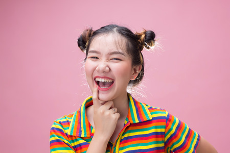 Pretty asian woman smiling with happiness on pink backgroundの写真素材