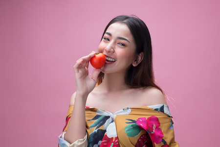 Young pretty asian woman holding a ripe tomato with happinessの写真素材