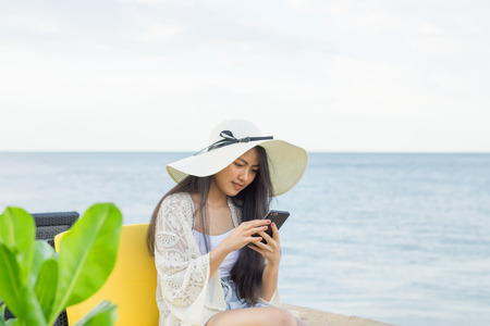 Young pretty asian woman enjoy with cellphone on the tropical beachの写真素材